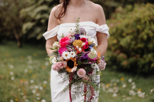 Bride stands in the garden ready for wedding holding bouquet