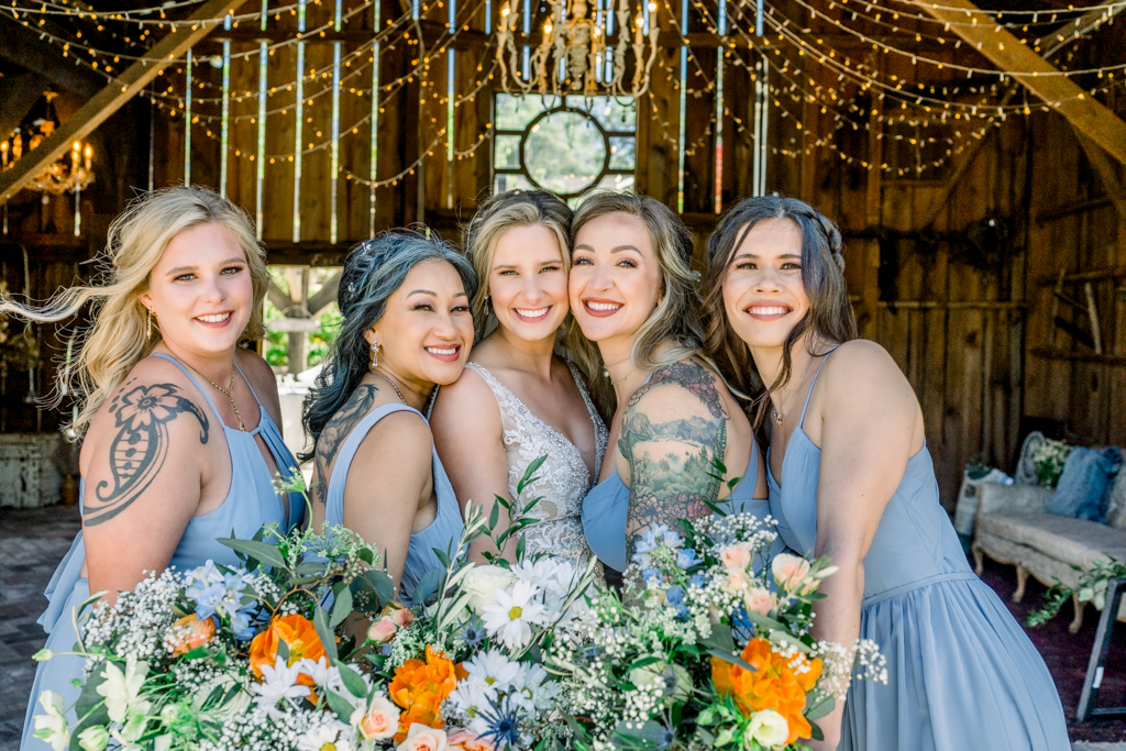 Bride in the middle bridesmaids on either side holding out their bouquet