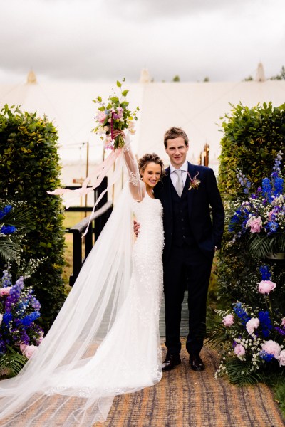 Bride and groom hug embrace fence farm garden scenery bouquet in the air arm raised