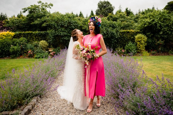 Woman wearing pink and bride laugh in garden