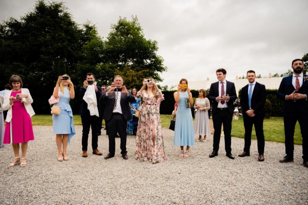 Family shot women and men in suits take picture of cameraman