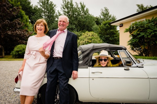 Mother father and woman with hat on sits in front seat of car