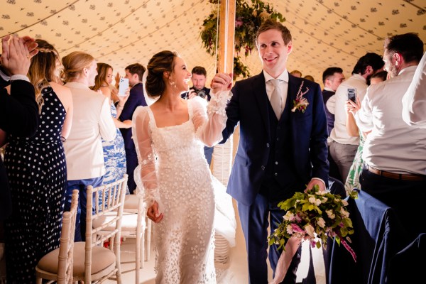 Bride and groom enter ballroom with guests clapping