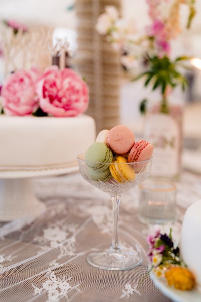 Macarons beside white wedding cake pink roses flowers