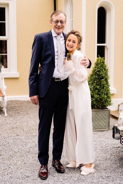 Bride and father outside at wedding car they hug