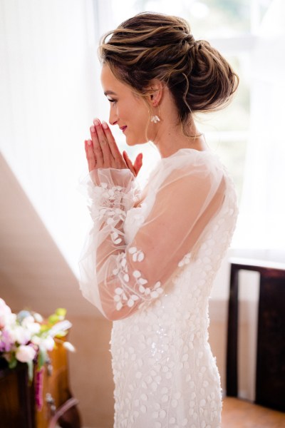 Bride places hands up to face lace floral design on arms