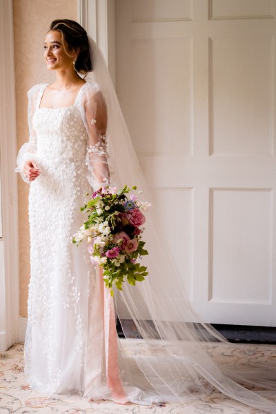 Bride looks out the window holding bouquet