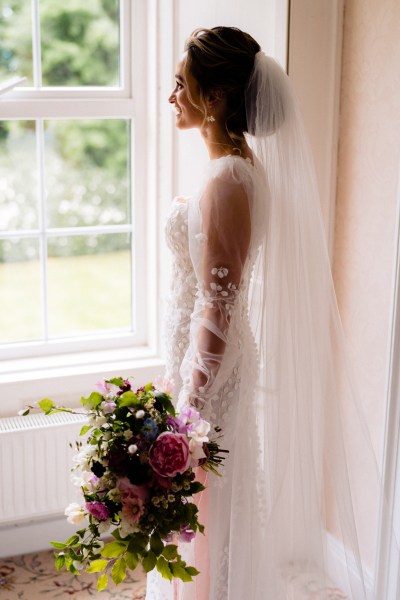 Bride looks out the window holding bouquet