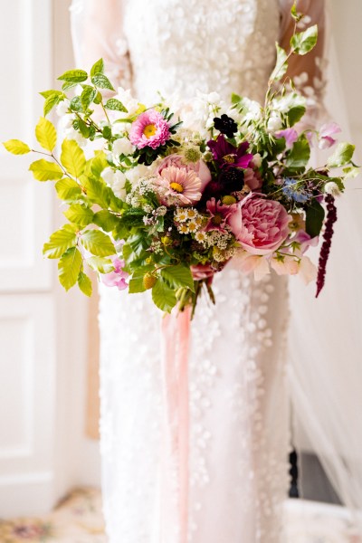 Bride stands at the window holding bouquet close up