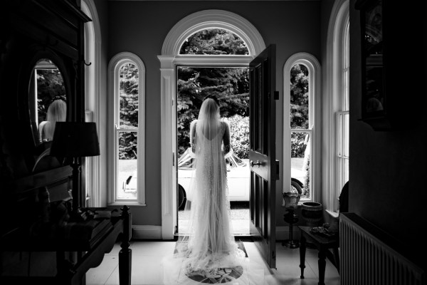 Black and white photo of bride exiting family home