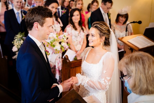 Bride and groom hold hands at the alter