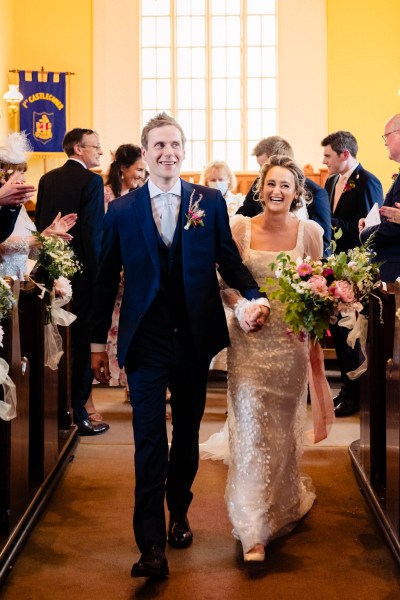 Photo of bride and groom just wet exiting church all smiles