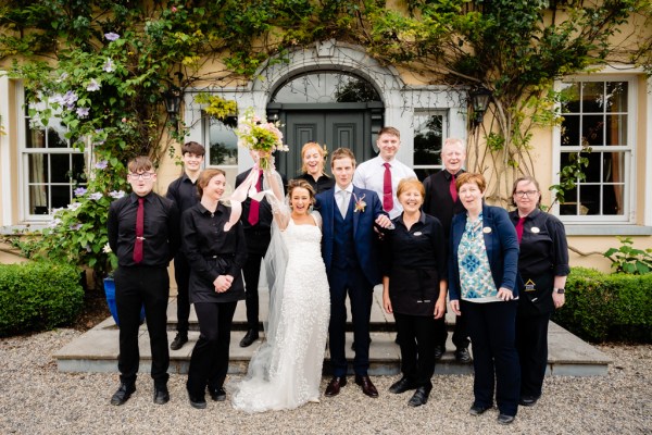 Bride groom and staff members pose for a photo