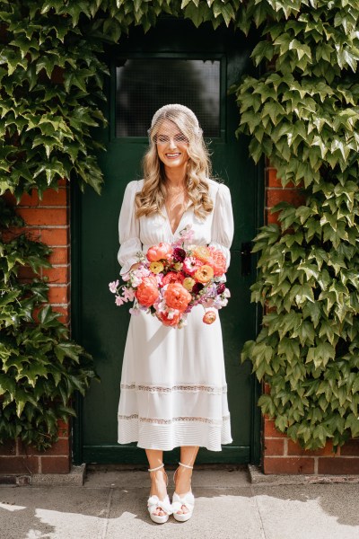 Bride on her own holding orange bright flower bouquet