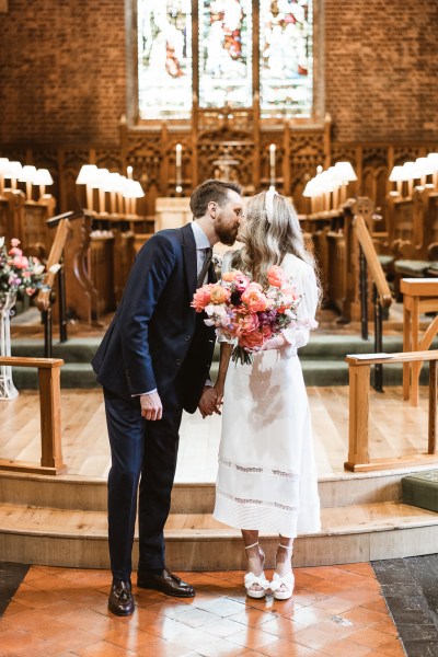 Bride and groom kiss at the alter to church