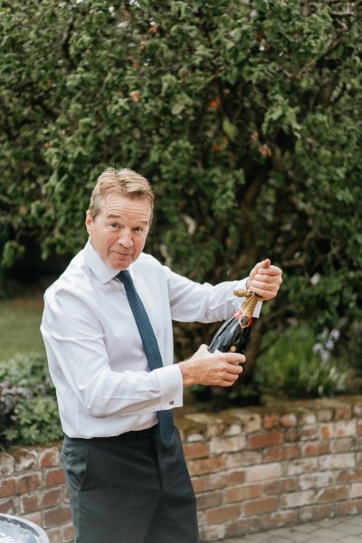 Father opens bottle of champagne