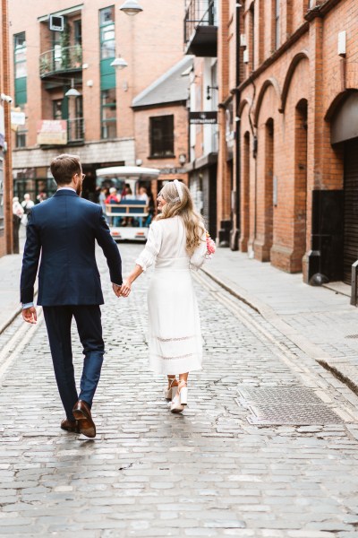 Bride and groom walking through Temple Bar bricked tiles