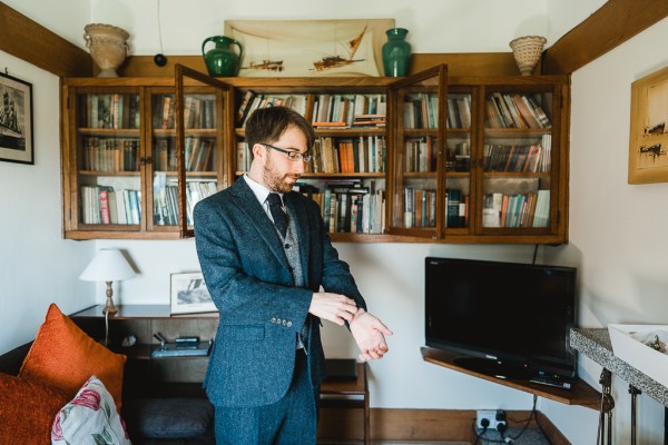 Groom fixing arms on suit and cufflinks