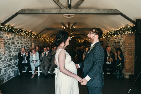 Bride and groom hold hands at the alter