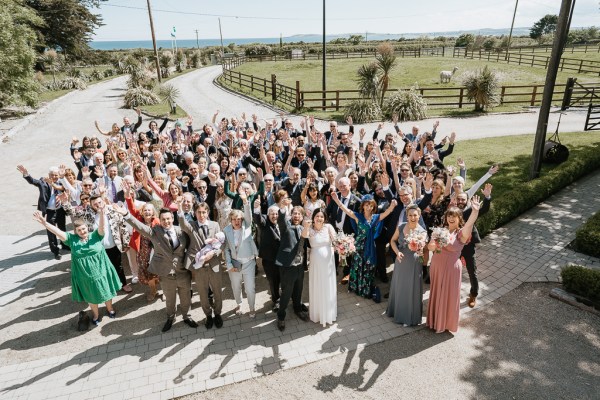 Group portrait photo bride groom bridesmaids groomsmen and guests pose for a photo down below