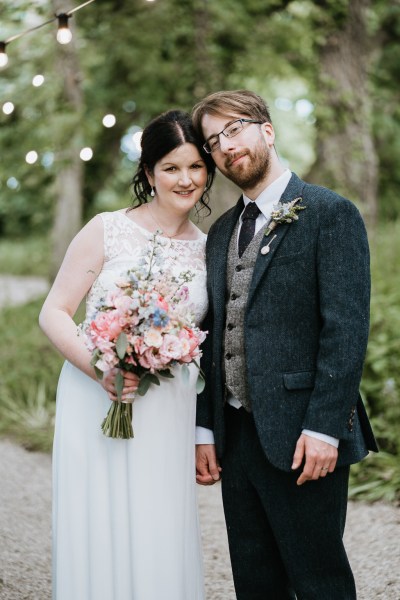 Bride and groom pose for a photo in the garden