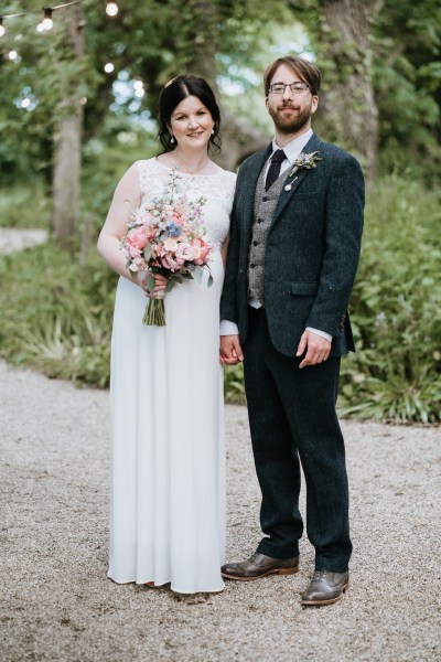 Bride and groom pose for a photo in the garden