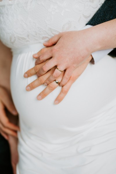 Bride and groom cup the pregnant belly stomach