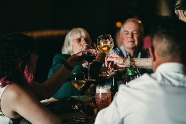 Guests sit and cheers with wine and pints