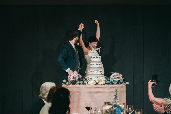 Bride and groom cut the white wedding cake cheers celebrating flowers