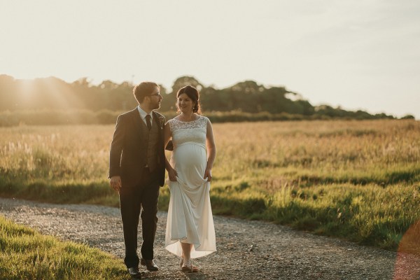 Bride and groom walk along pathway in park forest