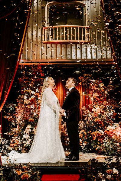 Bride and groom at alter confetti flowers drop on couple