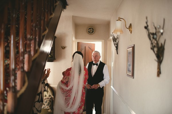 Wife wears bridal veil stands beside husband wearing suit and bowtie