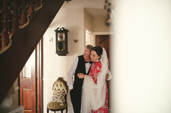 Wife wears bridal veil stands beside husband wearing suit and bowtie