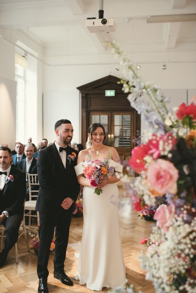 Bride and groom wed at the top of alter ceremony beside bed of flowers/roses