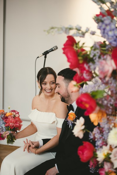 Microphone behind couple bride and groom beaming beside bed of flowers