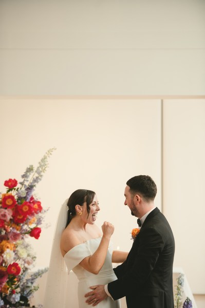 Bride and groom smile and gesture to each other