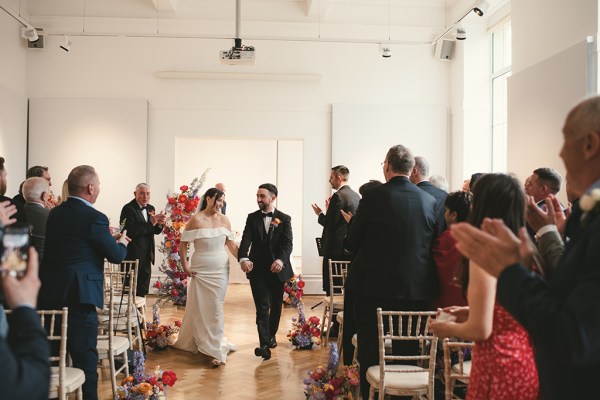 Bride and groom exit wedding ceremony guests stand and clap