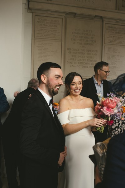 Bride and groom chat to guests she holds her bouquet