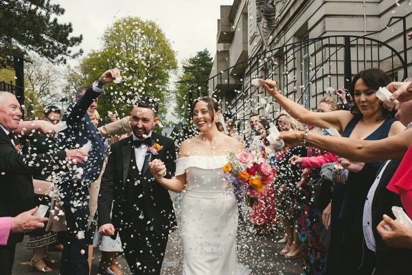 Confetti being thrown over couple by guests bride and groom