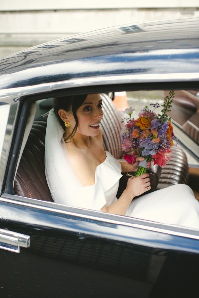 Bride looks out of wedding car window as she sits beside groom