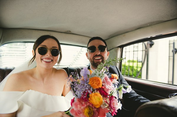 Groom beside bride holding bouquet roses flowers in wedding car