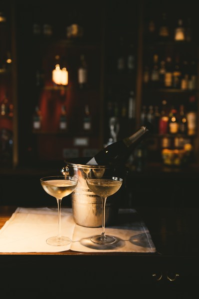 Dark bar pub setting champagne bottle in ice bucket and two glasses