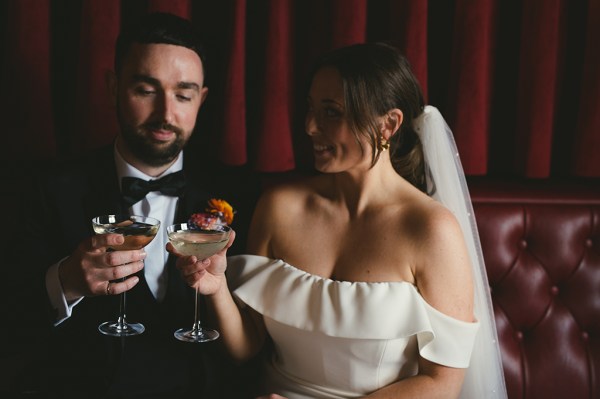 Bride and groom cheers with cocktails in hands