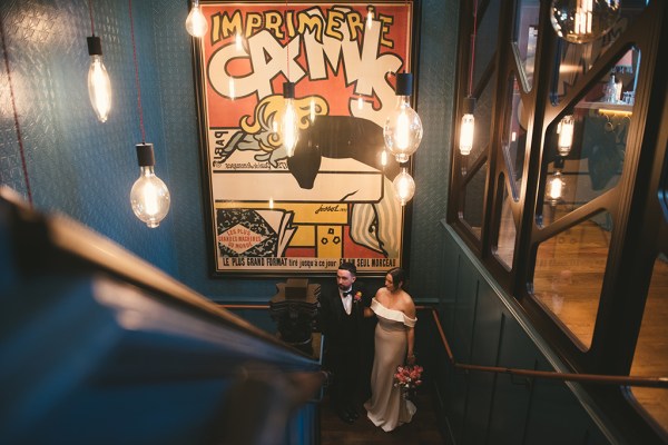 Bride and groom stand before staircase