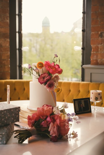 White wedding cake covered in orange flowers yellow couch