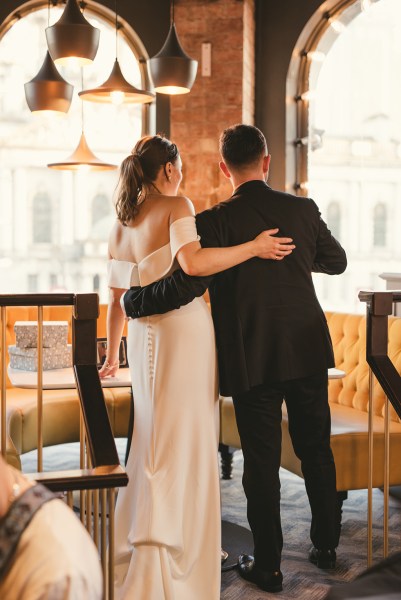 Shot of bride and groom from behind arms around each other