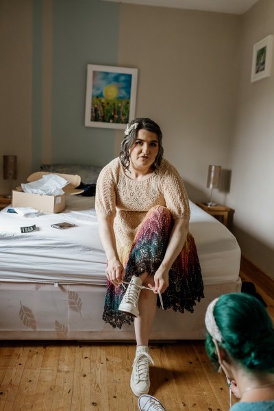 Bride puts her sneakers on as she gets ready for wedding