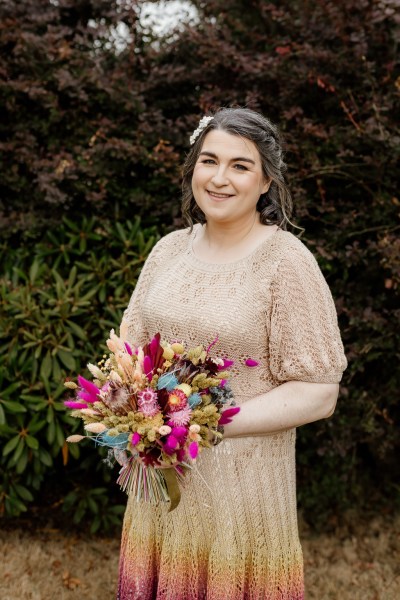 Bride stands holding bouquet colourful flowers in hand