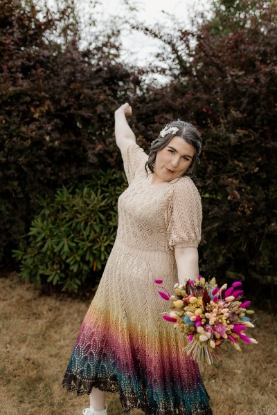 Bride stands holding bouquet flowers cheers hand in the air