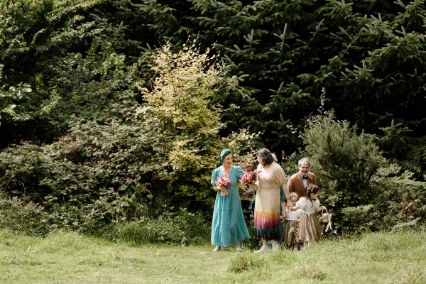 Bridesmaid bride and little girls walk up the trail towards ceremony